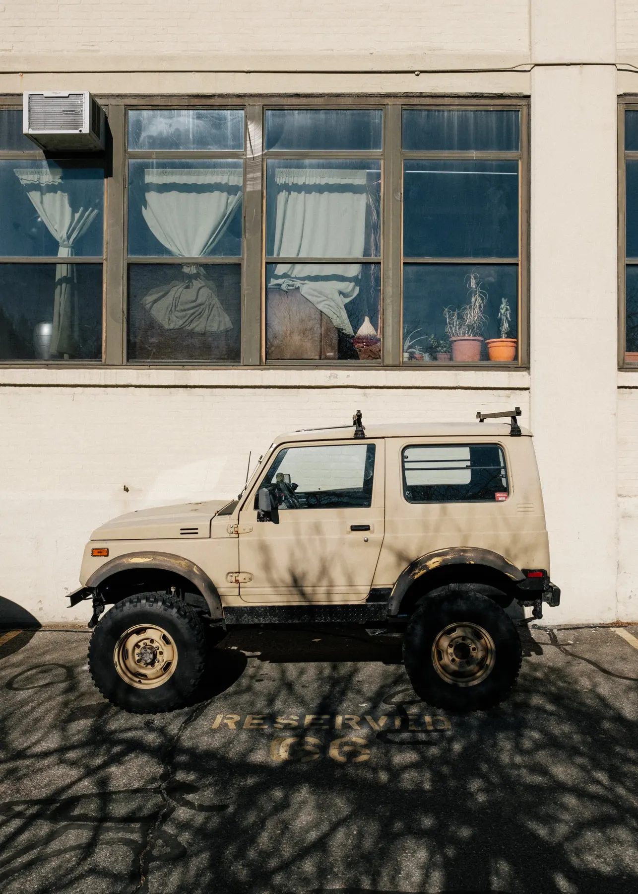 Beige off-roader parked below windows full of plants