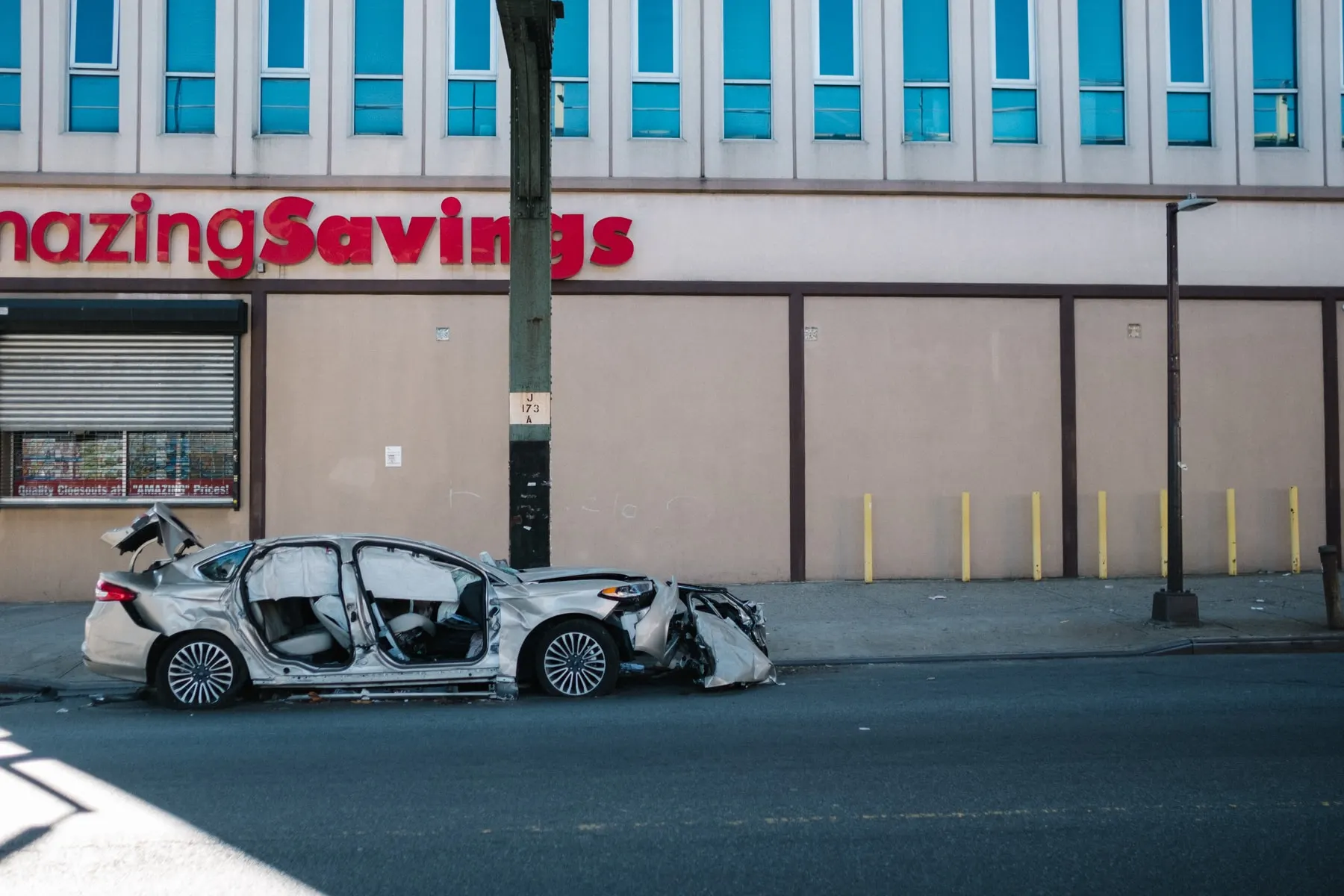 Wrecked silver car on the road outside a discount store