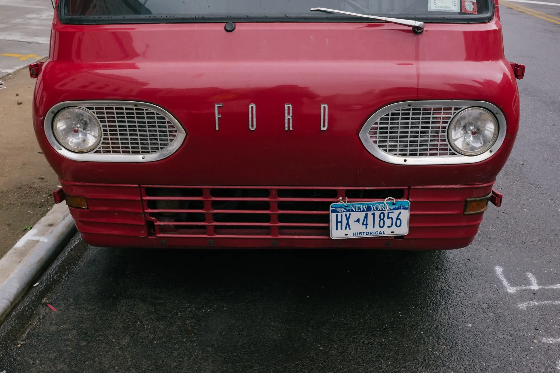 Front of a red Ford van with a historical plate