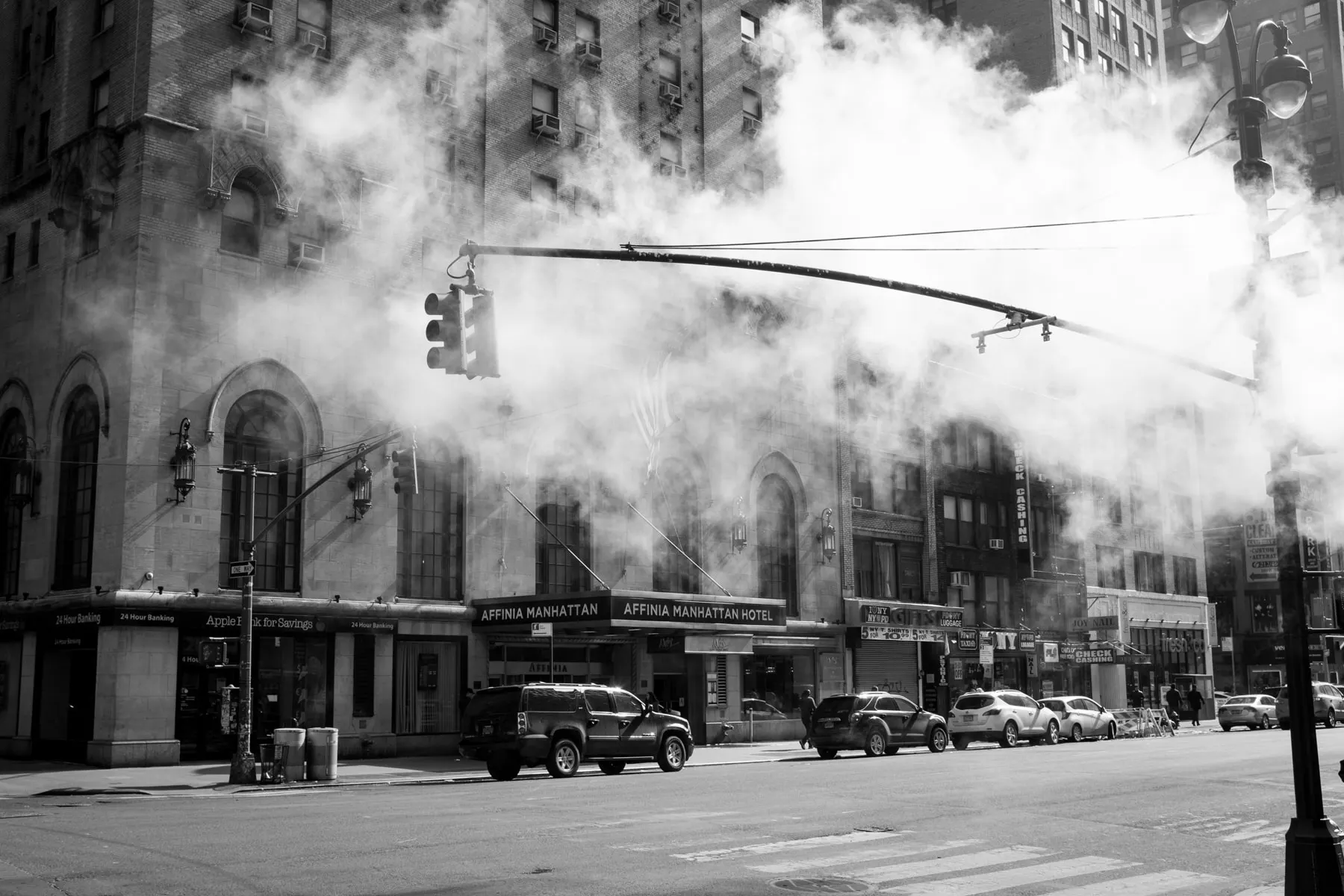 Steam pours across a street lined with older buildings
