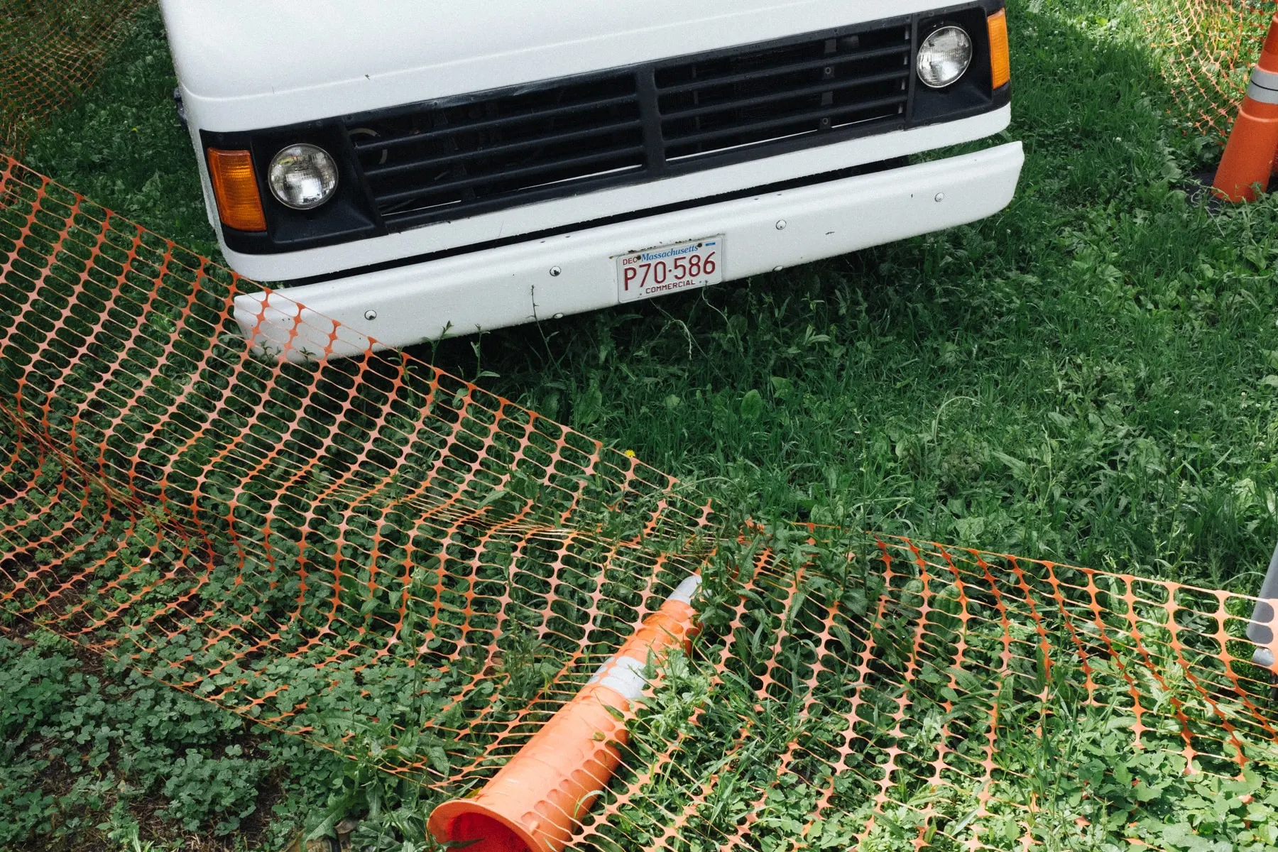 Orange fencing and a fallen cone in front of a white truck