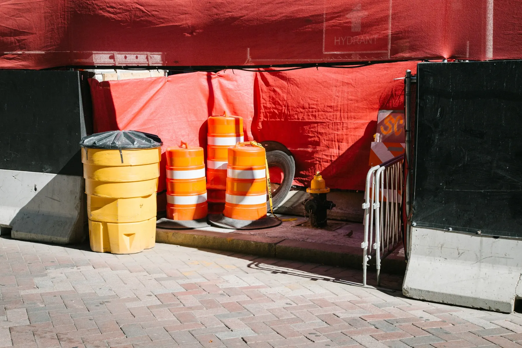 Barrels and cones under red netting at a building site