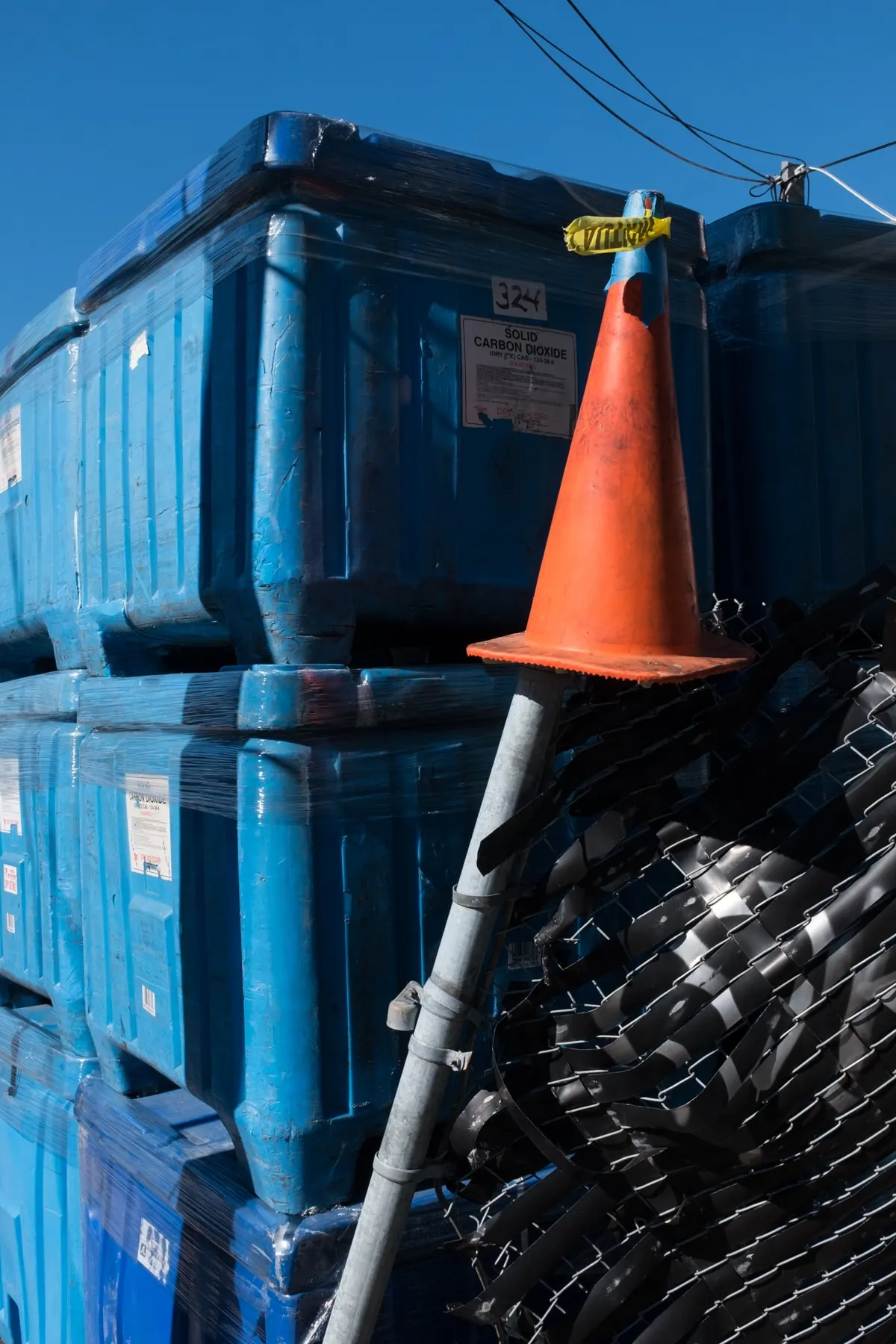Cone balanced on a post beside stacked blue containers
